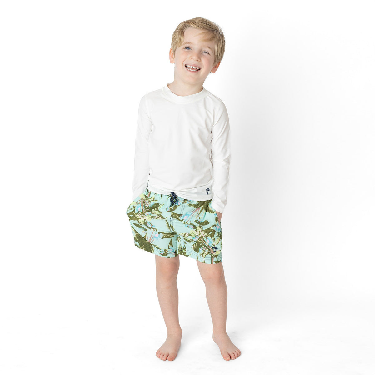 Boys Mint Tropics swim trunks on model showing fit and above-the-knee length.