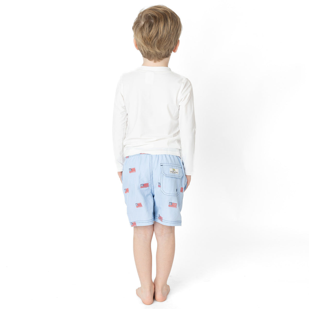 Boys light blue swim trunks with flag print and elastic waistband, comfortable kids swimwear from back.