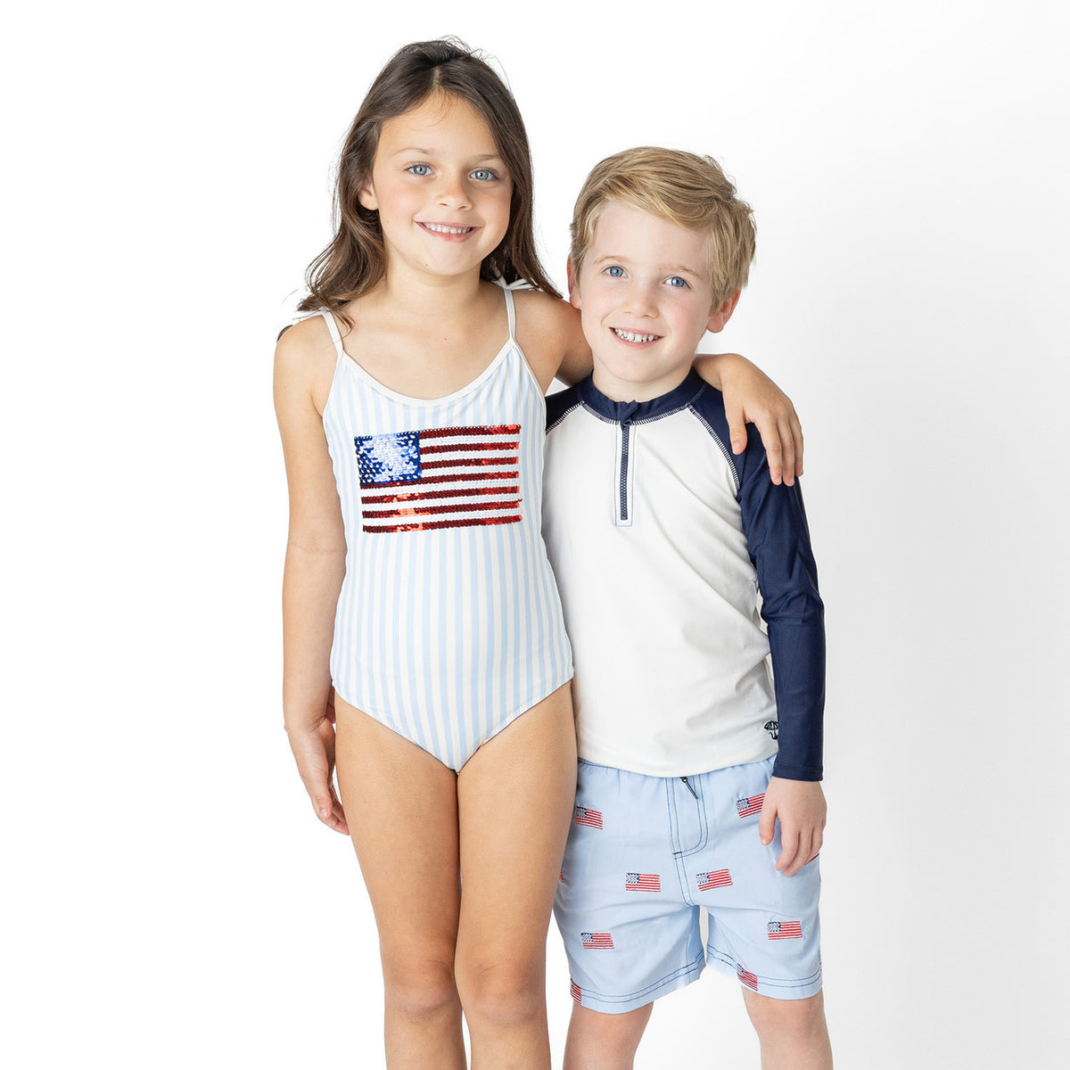 Boys Americana swim trunks styled with coordinating swimwear, patriotic kids swimwear look.