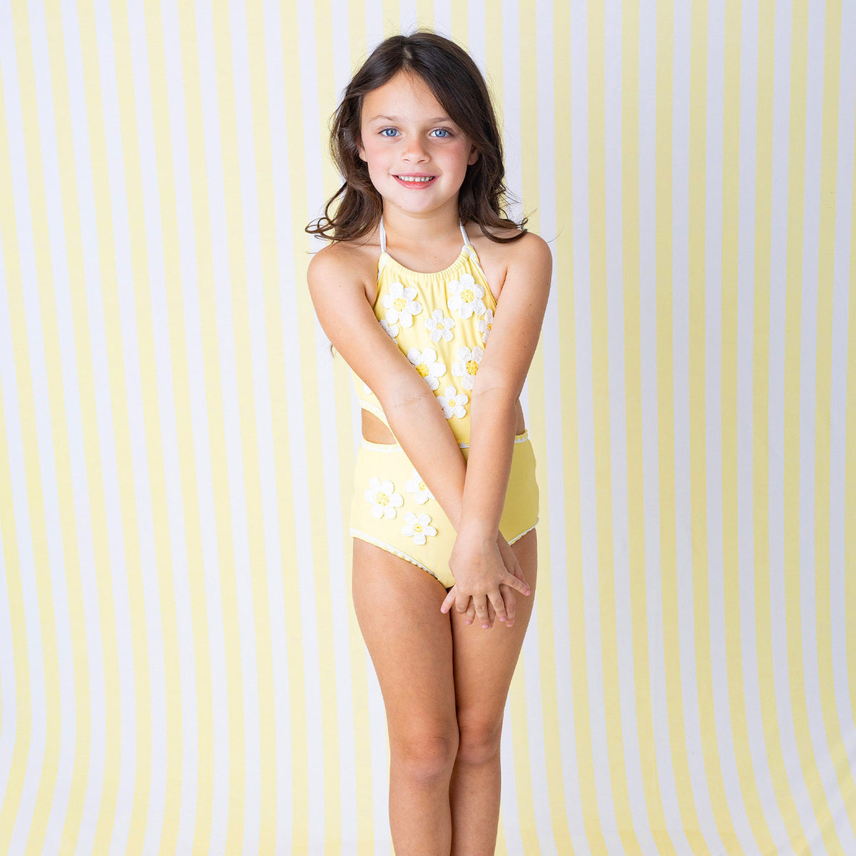 Girls Butter Yellow Daisy one piece swimsuit on model with halter neckline detail.