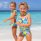 Girls citrus print ruffle one piece swimsuit, colorful kids swimwear shown on models at the beach, perfect for summer vacation.