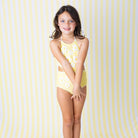 Girls Butter Yellow Daisy one piece swimsuit on model with halter neckline detail.