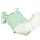 Highlighing the front of the Shimmer Mint one-shoulder suit by Shade Critters, with the oversized shoulder ruffles and soft metallic sparkle clearly visible. The pleated tutu skirt is arranged to showcase its full volume.